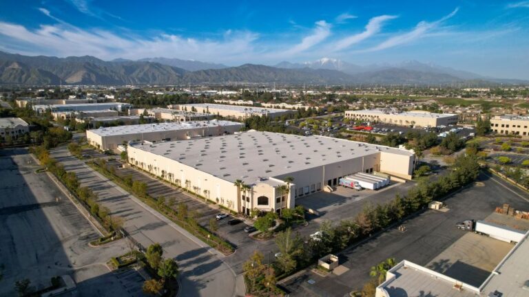 Aerial view of Paramount Logistics headquarters and warehouse facilities, showing expansive industrial buildings and surrounding landscape.