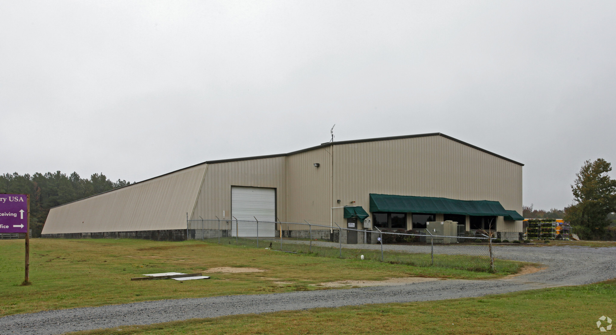 Exterior view of Orange Warehouse Corporation's headquarters and warehouse, showcasing a large industrial building surrounded by greenery.