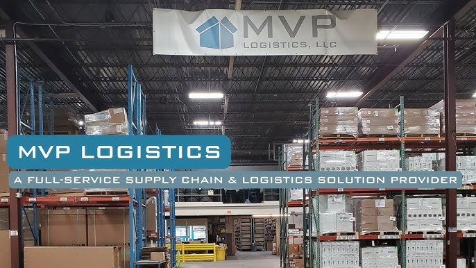 Interior of an MVP Logistics warehouse with pallet racking, stored goods, and a company banner.
