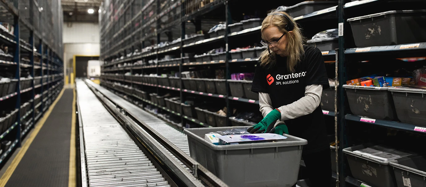 Granterion 3PL Solutions warehouse employee using phone headset, ensuring order accuracy amidst organized shelves.