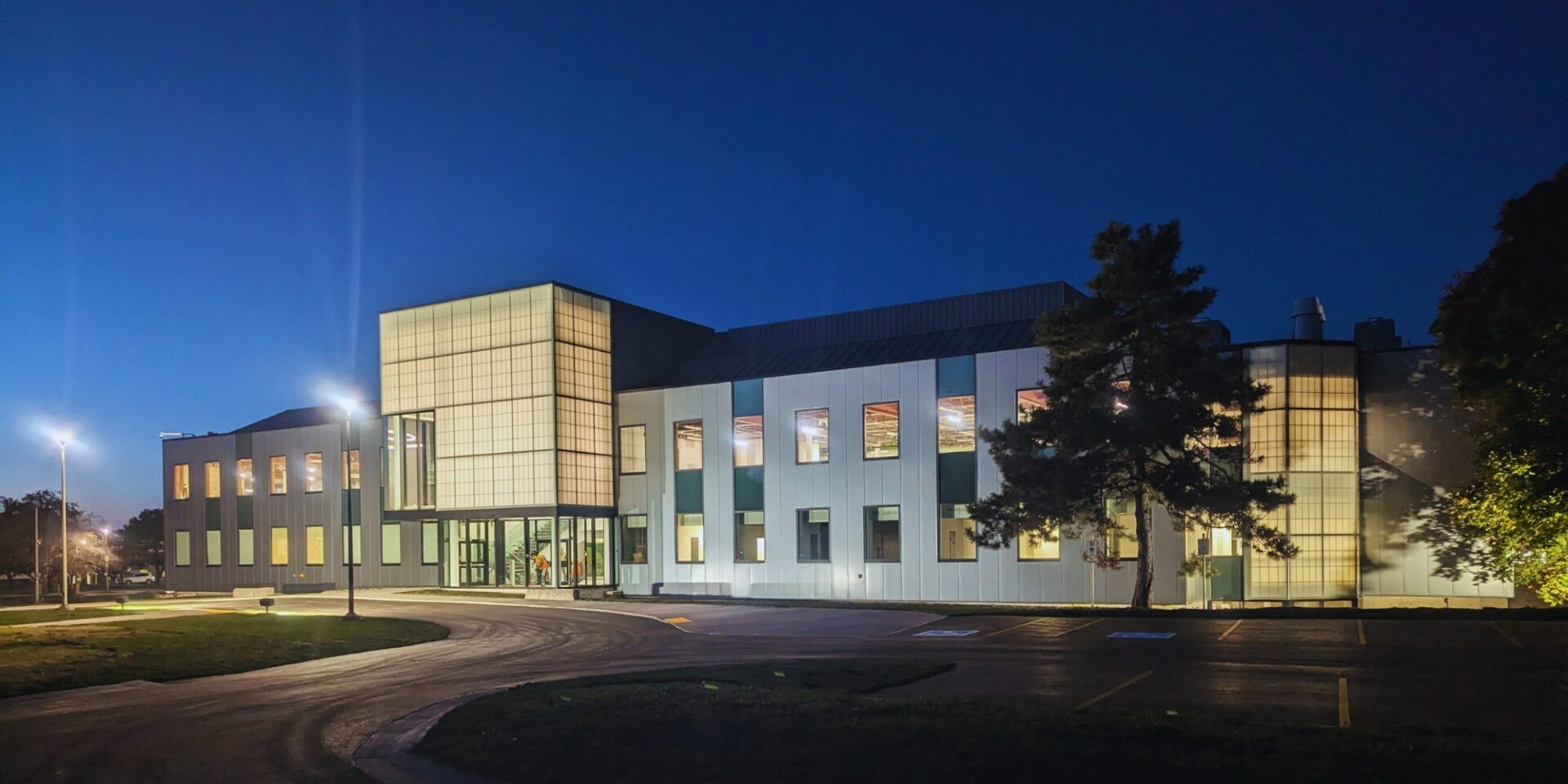 Night view of Niagara Prep Hub's modern headquarters and warehouse, featuring illuminated exterior and glass architecture.