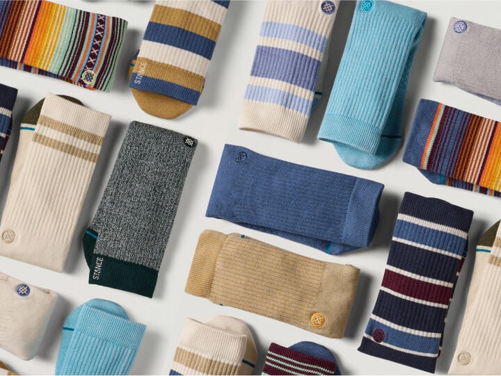 Stance presents a bold, contemporary brand identity with a focus on vibrant colors and playful design elements. The website features a clean, modern layout with high-contrast imagery showcasing colorful socks against striking backgrounds like Halloween themes with skulls and orange accents. The brand employs a mix of lifestyle photography and product shots, emphasizing the fun, expressive nature of their designs. The visual aesthetic balances performance-oriented messaging with street-style fashion sensibilities. Product imagery is crisp and detailed, often featuring multiple colorways displayed on clean white backgrounds. The overall design language suggests a premium yet accessible brand that doesn't take itself too seriously, using seasonal themes like Halloween to create engaging, themed collections that appeal to fashion-conscious consumers seeking both style and comfort.
